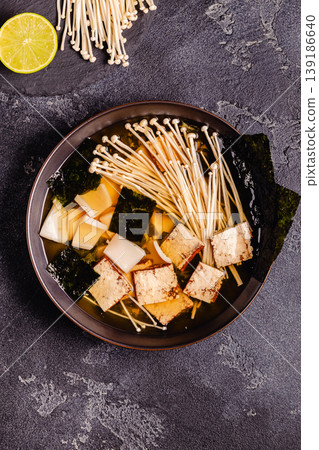 Asian-style soup with squid, tofu and enoki mushrooms. Asian-style soup with squid, tofu and enoki mushrooms. 139186640