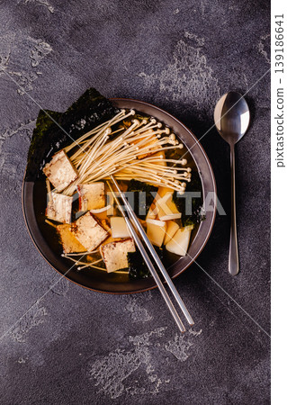 Asian-style soup with squid, tofu and enoki mushrooms. Asian-style soup with squid, tofu and enoki mushrooms. 139186641