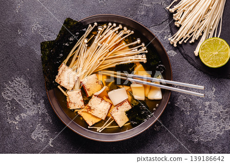 Asian-style soup with squid, tofu and enoki mushrooms. Asian-style soup with squid, tofu and enoki mushrooms. 139186642