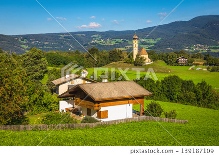 Typical scattered alpine village with cute church on the meadow 139187109
