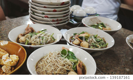 Group of Thai boat noodle bowls with pork and meatballs on restaurant table 139187161
