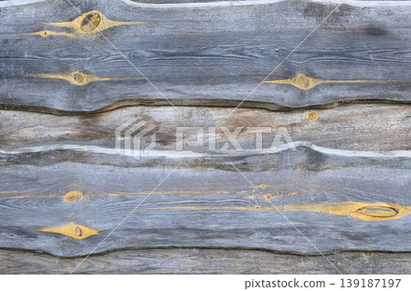 Rustic background of old gray wooden boards with noticeable knots and wavy edges. Natural texture of aged wood with horizontal lines. 139187197