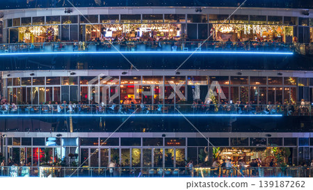 Circular building with different restaurants at each floor in the heart of Dubai Marina district night timelapse. 139187262