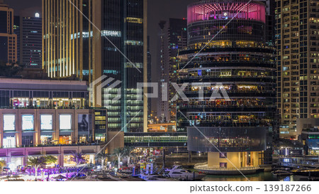 Aerial view of Dubai Marina with shopping mall, restaurants, towers and yachts night timelapse, United Arab Emirates. Aerial view of Dubai Marina with shopping mall, restaurants, towers and yachts night timelapse, United Arab Emirates. 139187266
