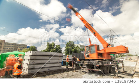 Unloading concrete plates from truck by crane at road construction site timelapse. Unloading concrete plates from truck by crane at road construction site timelapse. 139187340
