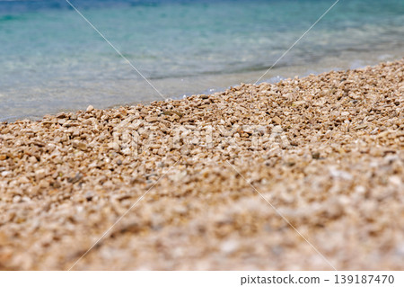 Close up of pebble beach texture with clear turquoise sea water. Shallow depth of field and copy space. Close up of pebble beach texture with clear turquoise sea water. Shallow depth of field and copy space. 139187470