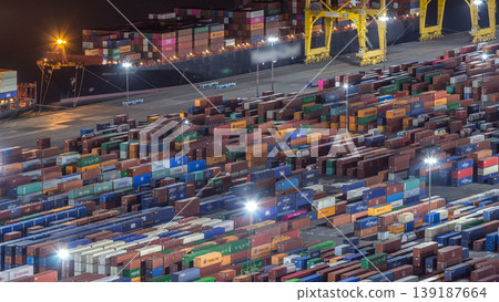 Seaport and loading docks at the port with cranes and multi-colored cargo containers night timelapse 139187664