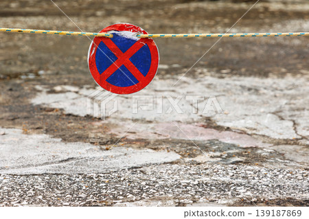 Closeup of a red blue no stopping traffic sign blocking walkway. Urban restriction and traffic regulation concept with copy space. Closeup of a red blue no stopping traffic sign blocking walkway. Urban restriction and traffic regulation concept with copy space. 139187869
