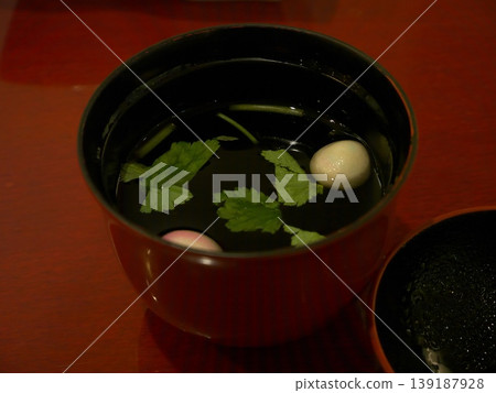 盛在黑色漆碗中的清湯,湯裡漂浮著三葉芹(日本歐芹)和麵筋(小麥麵筋)。 盛在黑色漆碗中的清湯,湯裡漂浮著三葉芹(日本歐芹)和麵筋(小麥麵筋)。 139187928