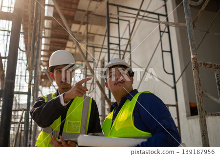Construction project planning worksite team collaboration urban setting close-up view professional guidance 139187956