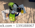 Construction workers collaborating on project planning job site work environment aerial view teamwork and efficiency 139188067