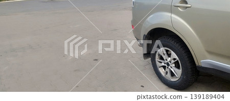 The rear of a beige SUV is shown parked on a paved surface. The focus is on the clean alloy wheel and black tire, highlighting the vehicle's sturdy design and readiness for the open road 139189404