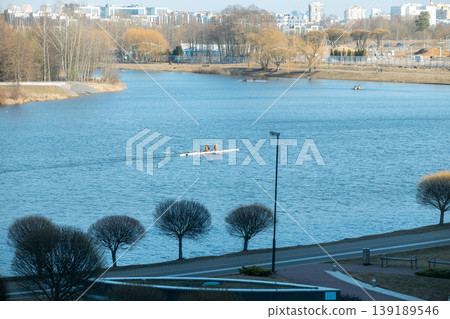 Rowers training on a wide city river with urban skyline Rowers training on a wide city river with urban skyline 139189546