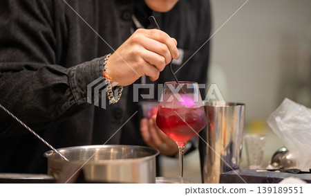 Close-up of a professional bartender stirring a red cocktail Close-up of a professional bartender stirring a red cocktail 139189551