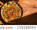 Traditional French quiche with fish and spinach, top view of cooling freshly baked quiche on a wooden board in bright sunlight, traditional pastry, copy space for text 139189565