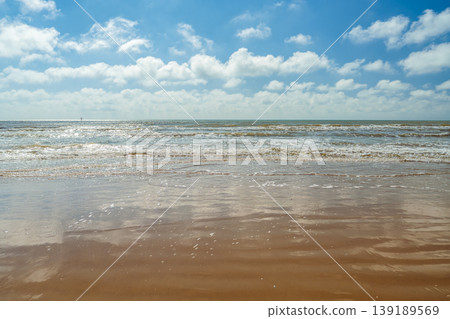 poster inviting you to a vacation on secluded Mediterranean beaches, a resort overlooking a magnificent sea view from a sandy beach, the blue sky reflected on the wet sand, copy space for text poster inviting you to a vacation on secluded Mediterranean beaches, a resort overlooking a magnificent sea view from a sandy beach, the blue sky reflected on the wet sand, copy space for text 139189569