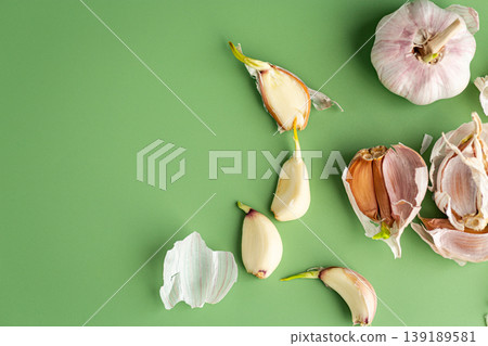 fresh garlic cloves with peel on green background 139189581