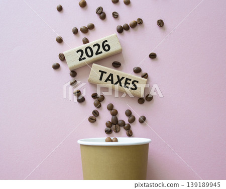 2026 Taxes symbol. Concept words 2026 Taxes on beautiful wooden picture frame. Beautiful pink background with coffee cup and coffee beans. Business and 2026 Taxes concept. Copy space. 2026 Taxes symbol. Concept words 2026 Taxes on beautiful wooden picture frame. Beautiful pink background with coffee cup and coffee beans. Business and 2026 Taxes concept. Copy space. 139189945