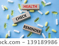 Health check reminder symbol. Concept words Health check reminder on wooden blocks. Beautiful pink background with pills. Healthcare and Health check reminder concept. Copy space. 139189986
