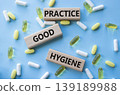 PRACTICE GOOD HYGIENE symbol. Concept words PRACTICE GOOD HYGIENE on wooden blocks. Beautiful pink background with pills. Healthcare and PRACTICE GOOD HYGIENE concept. Copy space. 139189988