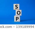 SOP - Standard Operating Procedure symbol. Wooden blocks with words SOP. Beautiful blue background. Business and SOP concept. Copy space. 139189994