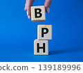 BPH - Benign Prostatic Hyperplasia symbol. Wooden cubes with word BPH. Businessman hand. Beautiful blue background. Medical and BPH concept. Copy space. 139189996
