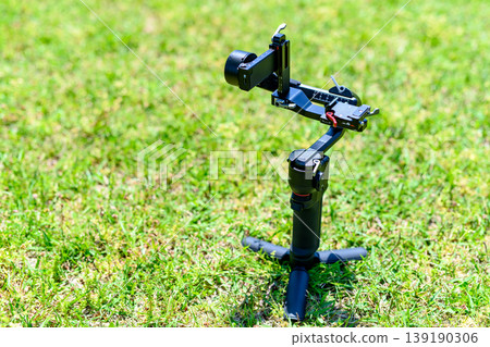 Preparing for video shooting with a mirrorless camera: Setting up the shooting gimbal in the grass, and the stabilizer... Preparing for video shooting with a mirrorless camera: Setting up the shooting gimbal in the grass, and the stabilizer... 139190306