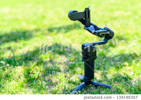 Preparing for video shooting with a mirrorless camera: Setting up the shooting gimbal in the grass, and the stabilizer... Preparing for video shooting with a mirrorless camera: Setting up the shooting gimbal in the grass, and the stabilizer... 139190307