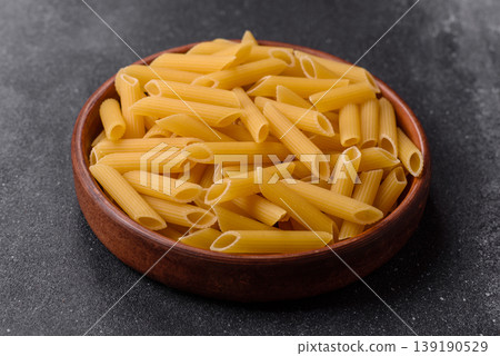 Italian uncooked dry penne regate pasta ready for cooking. Dry penne pasta Italian uncooked dry penne regate pasta ready for cooking. Dry penne pasta 139190529