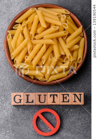 Italian uncooked dry penne regatta pasta with a gluten prohibition sign. The gluten prohibition sign 139190544