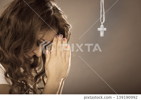 Woman praying to god jesus with cross necklace. Woman praying to god jesus with cross necklace. 139190992