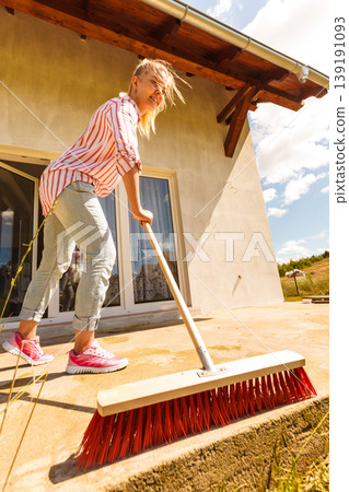 Woman cleaning patio using brush broom Woman cleaning patio using brush broom 139191093