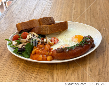 Sausage with fried eggs, beans, mushrooms, salad, and toasted bread on plate. Breakfast meal, protein intake, morning routine, hearty portion, and cafe dining experience. Sausage with fried eggs, beans, mushrooms, salad, and toasted bread on plate. Breakfast meal, protein intake, morning routine, hearty portion, and cafe dining experience. 139191268