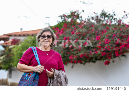 Happy senior woman concept. Senior travel concept. Senior woman at the beautiful colonial town of Villa de Leyva in Colombia Happy senior woman concept. Senior travel concept. Senior woman at the beautiful colonial town of Villa de Leyva in Colombia 139191440