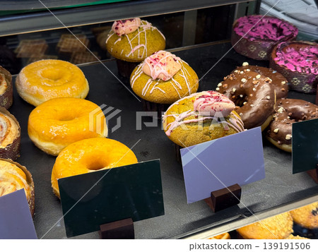 Assorted pastries and waffles displayed inside bakery showcase. Food selection, dessert variety, sweet snack, retail presentation, cafe interior, and consumer choice concept. Assorted pastries and waffles displayed inside bakery showcase. Food selection, dessert variety, sweet snack, retail presentation, cafe interior, and consumer choice concept. 139191506