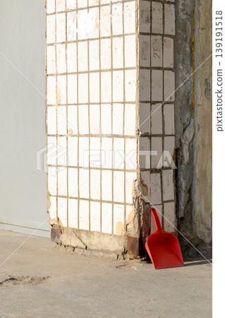 red plastic dustpan for trash lies in the corner by a wall faced with white square tiles red plastic dustpan for trash lies in the corner by a wall faced with white square tiles 139191518