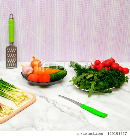 set of fresh vegetables and greens with kitchen utensils lies on a marble countertop in the kitchen set of fresh vegetables and greens with kitchen utensils lies on a marble countertop in the kitchen 139191557