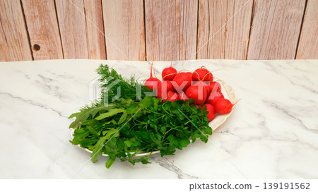 bunches of parsley dill and red radish on a white plate by a wooden wall bunches of parsley dill and red radish on a white plate by a wooden wall 139191562
