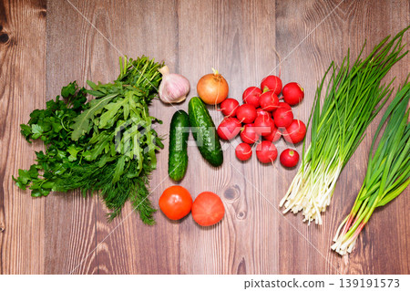 vegetable still life with tomatoes, cucumbers, radishes and greens, top view on a wooden floor vegetable still life with tomatoes, cucumbers, radishes and greens, top view on a wooden floor 139191573