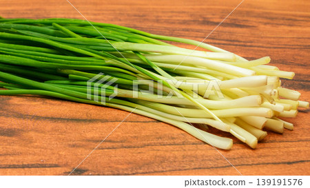 close up of white stems of green onions on a wooden background close up of white stems of green onions on a wooden background 139191576