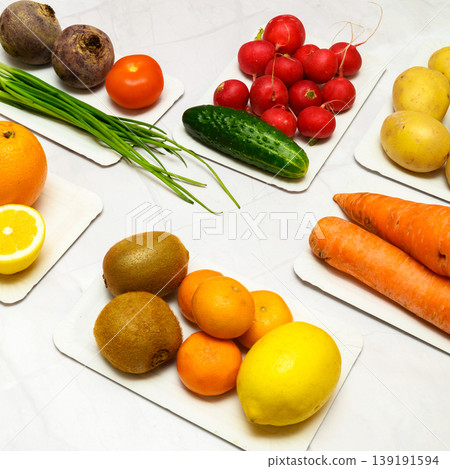 large set of vegetables and fruits on a light table including carrots potatoes radishes and kiwi 139191594