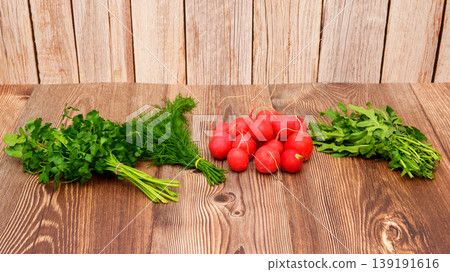 bunches of fresh parsley, dill, arugula and a pile of red radishes on a wooden table surface bunches of fresh parsley, dill, arugula and a pile of red radishes on a wooden table surface 139191616