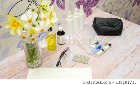 medical devices and pills in a blister on a table next to a vase of daffodils medical devices and pills in a blister on a table next to a vase of daffodils 139191713