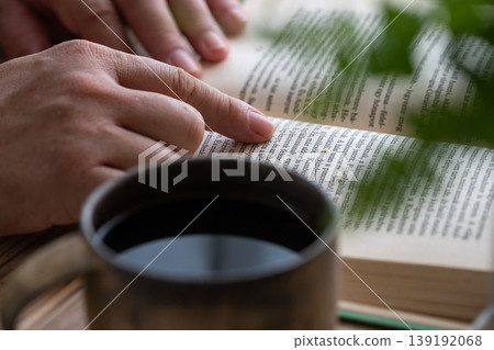 A man's hand while reading a book and drinking coffee. A man's hand while reading a book and drinking coffee. 139192068