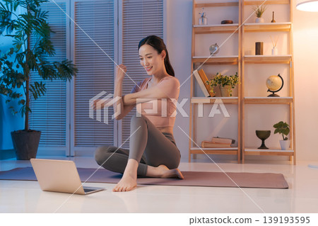 一位女士一邊做瑜珈一邊看著電腦。 139193595