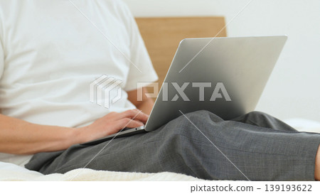 A man's hands using a laptop in bed A man's hands using a laptop in bed 139193622
