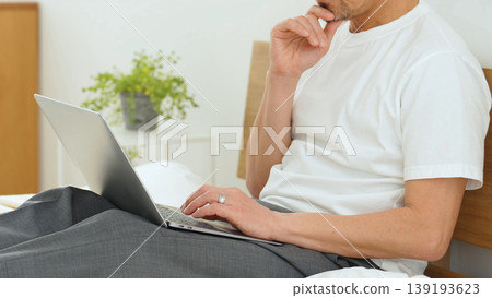 A man's hands using a laptop in bed A man's hands using a laptop in bed 139193623