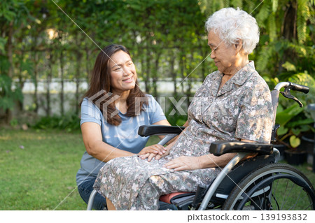 Caregiver help and care Asian senior woman patient sitting on wheelchair at nursing hospital ward, healthy strong medical. Caregiver help and care Asian senior woman patient sitting on wheelchair at nursing hospital ward, healthy strong medical. 139193832