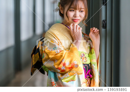 A 20-year-old woman in a furisode kimono stands by the window of a retro, antique Western-style mansion/studio. A 20-year-old woman in a furisode kimono stands by the window of a retro, antique Western-style mansion/studio. 139193891