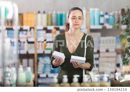 Middle-aged woman customer choosing pills in box in drugstore Middle-aged woman customer choosing pills in box in drugstore 139194210